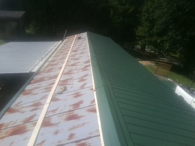 Old rusted panels beside newly installed green metal roofing — Wind Damage Roof Repair by Roofing Brothers in East Sandwich