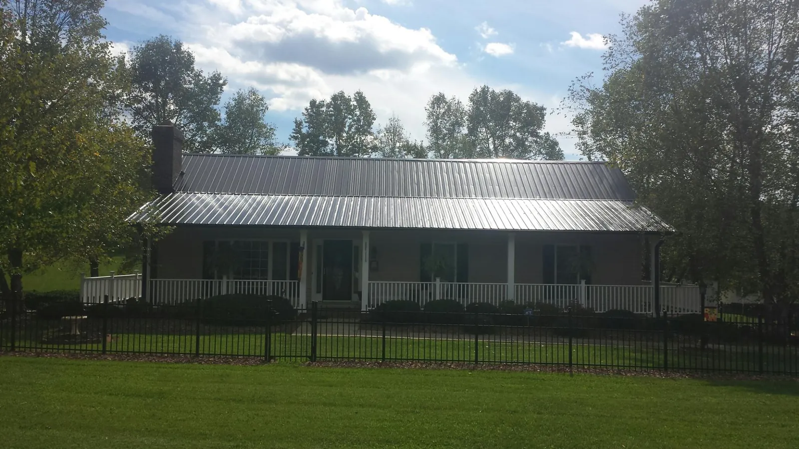 Gray metal roof on a brick ranch with a full width front porch — Gutter Guard Installation work by our crew in East Sandwich