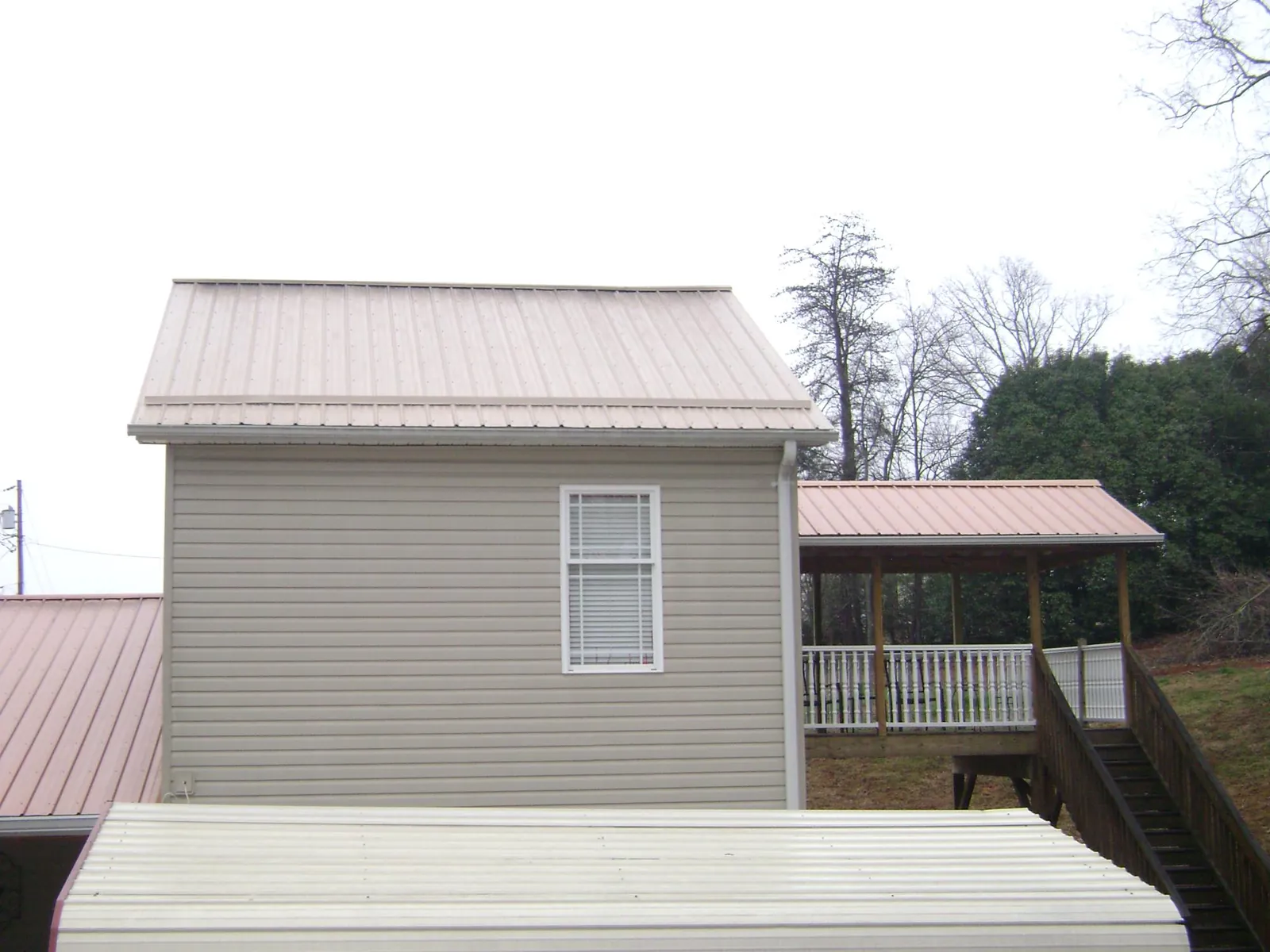 Tan metal roofs on a two story addition and attached porch, from a Roof Replacement job in East Sandwich