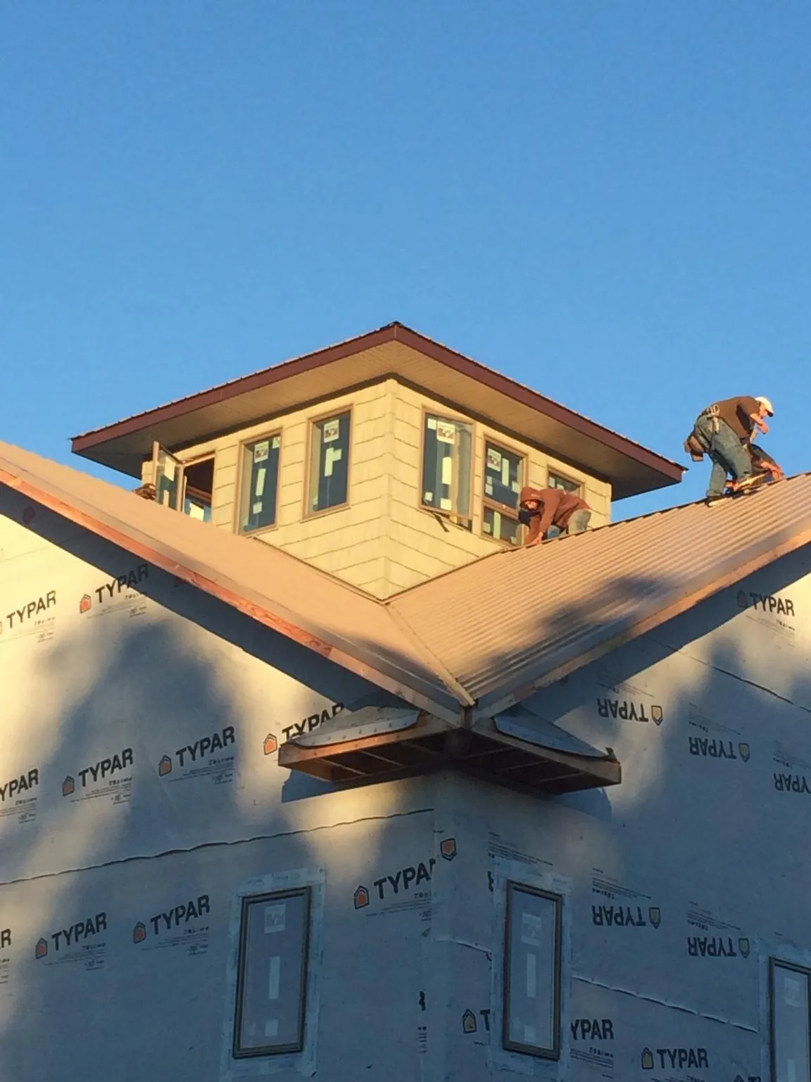 Roofers working around a rooftop cupola on a new metal roof at sunset — Roof Waterproofing in East Sandwich by Roofing Brothers
